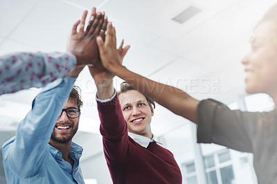 Buy stock photo Shot of a team of young go getters giving each other a high five in a modern office