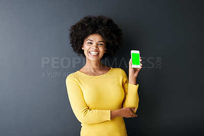 Buy stock photo Studio portrait of an attractive young woman holding up her mobile phone against a grey background