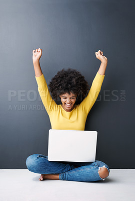 Buy stock photo Studio shot of an attractive young woman cheering while using her laptop against a grey background