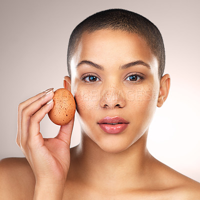 Buy stock photo Studio shot of a beautiful young woman holding a egg against her face