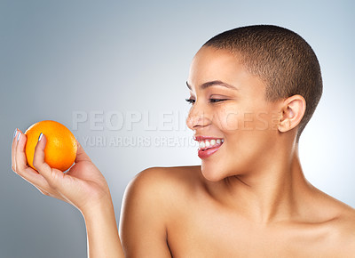 Buy stock photo Studio shot of a beautiful young woman posing with an orange against a grey background