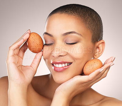 Buy stock photo Skincare, happy and woman with eggs in studio for natural, cosmetic and hydration facial treatment. Wellness, health and female model with poultry for face dermatology routine by gray background.