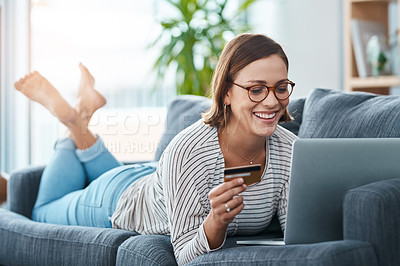 Buy stock photo Full length shot of a young woman using her laptop and credit card on the sofa at home