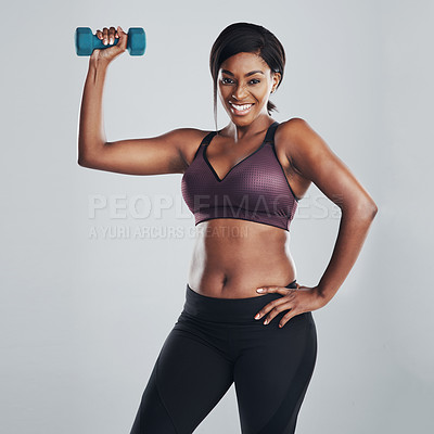 Buy stock photo Studio portrait of an attractive and fit young woman exercising with a dumbbell against a grey background