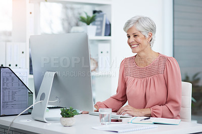 Buy stock photo Shot of a cheerful mature businesswoman working on a computer in her office