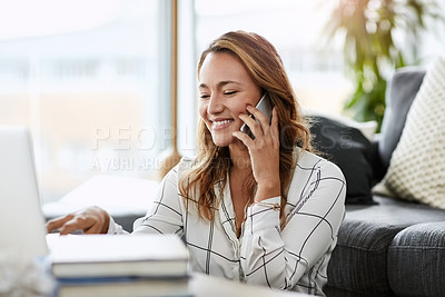 Buy stock photo Shot of attractive businesswoman taking a phone call while doing some work on her laptop at home