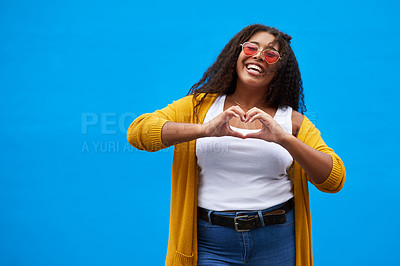 Buy stock photo Studio portrait of an attractive young woman showing a love sign against a blue background
