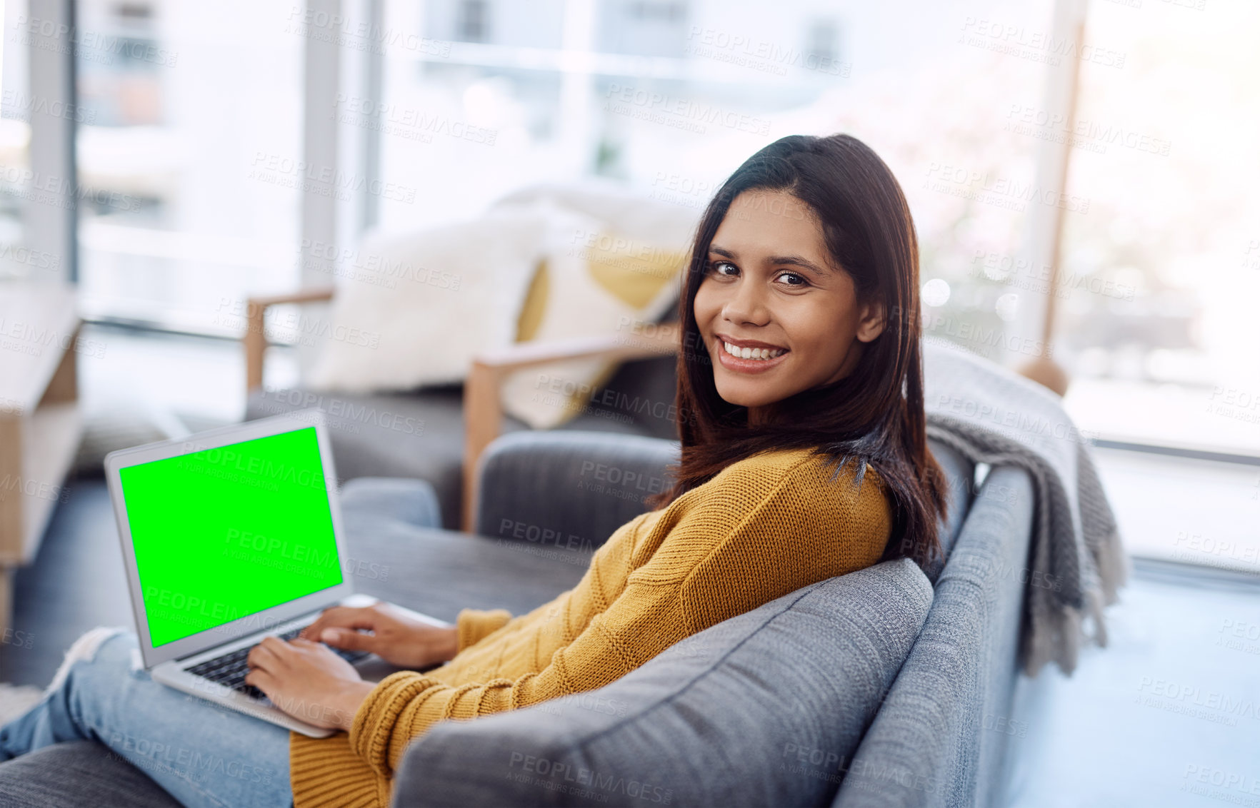 Buy stock photo Portrait of an attractive young woman using her laptop while relaxing on a sofa at home