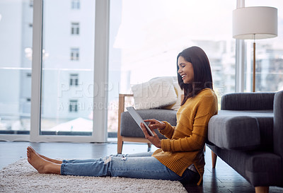 Buy stock photo Full length shot of an attractive young woman using her digital tablet while sitting down on the floor at home