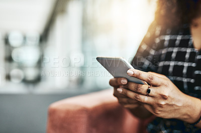 Buy stock photo Cropped shot of an unrecognizable businesswoman using a smartphone while sitting on a couch in a modern office