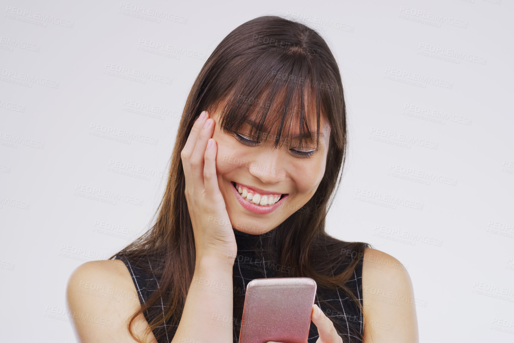 Buy stock photo Studio shot of a young woman using her cellphone against a grey background