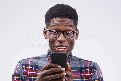Buy stock photo Studio shot of a young man looking surprised while using his cellphone