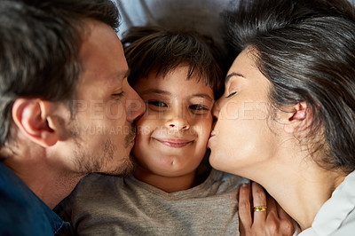 Buy stock photo Shot of a beautiful young couple kissing their young son on the cheeks at home