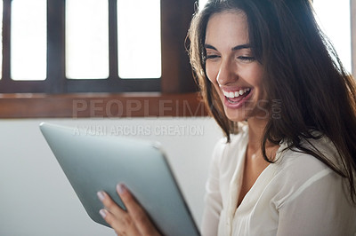 Buy stock photo Shot an attractive young woman using her digital tablet while relaxing at home