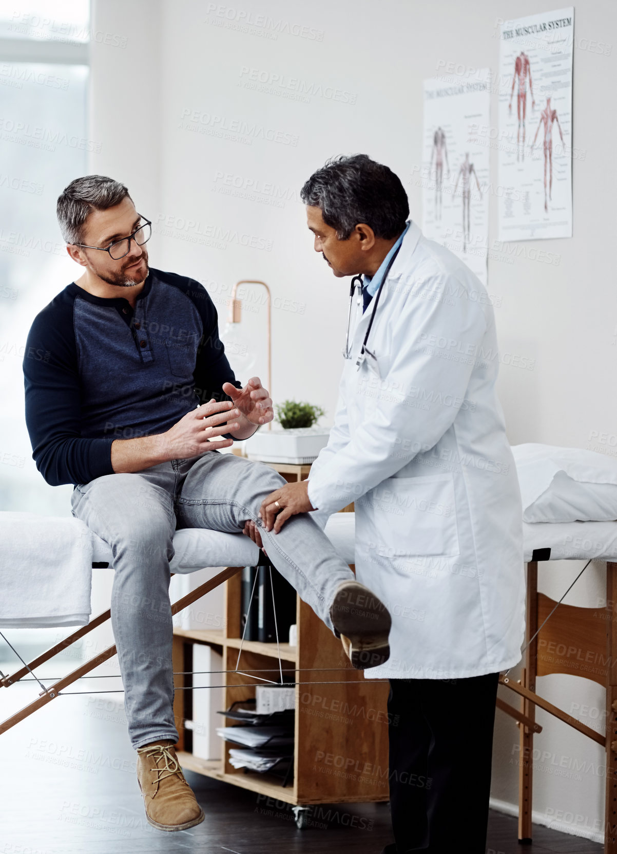 Buy stock photo Shot of a confident mature male doctor doing a checkup on a patient inside of a hospital during the day