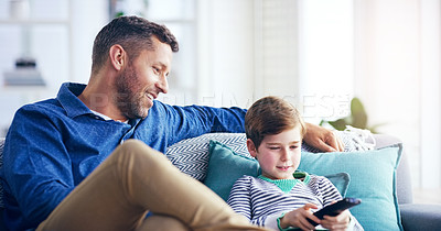 Buy stock photo Shot of a cheerful father and son relaxing on a couch and spending some time together indoors