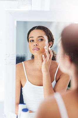 Buy stock photo Cropped shot of an attractive young woman applying moisturizer to her face