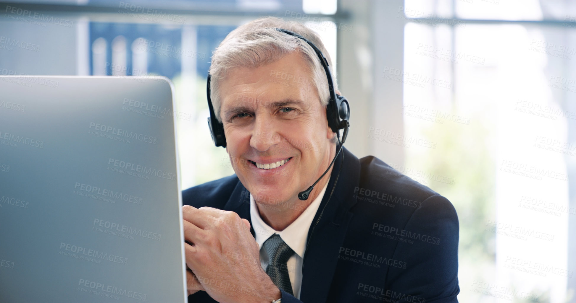 Buy stock photo Portrait of a mature businessman wearing headphones while working on a computer in an office