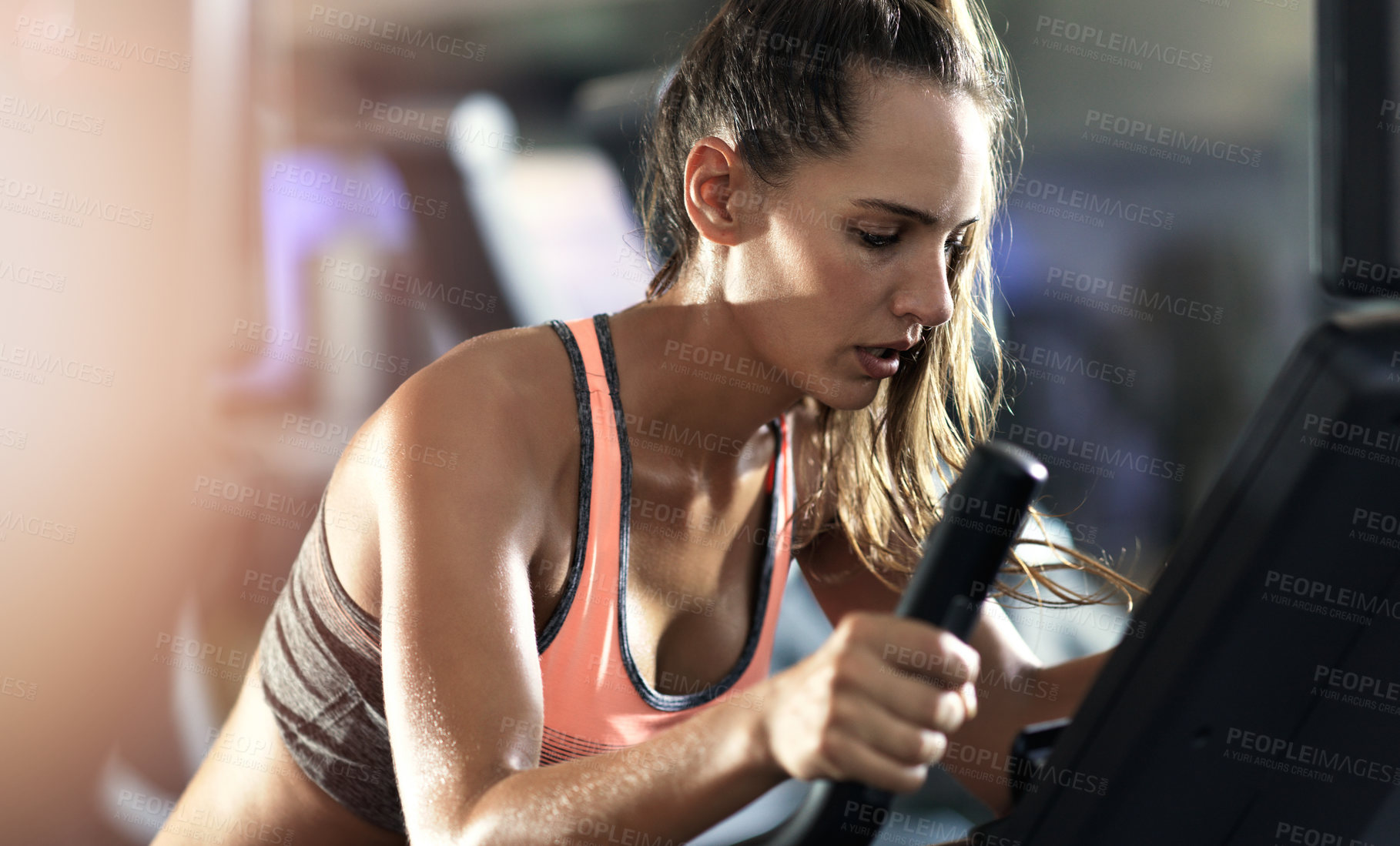 Buy stock photo Woman, marathon training and fitness in gym on elliptical machine for health, wellness and cardio endurance. Cyclist, exercise bike and performance on equipment, power challenge and intense workout