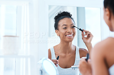 Buy stock photo Shot of a beautiful young woman applying mascara in her bathroom mirror