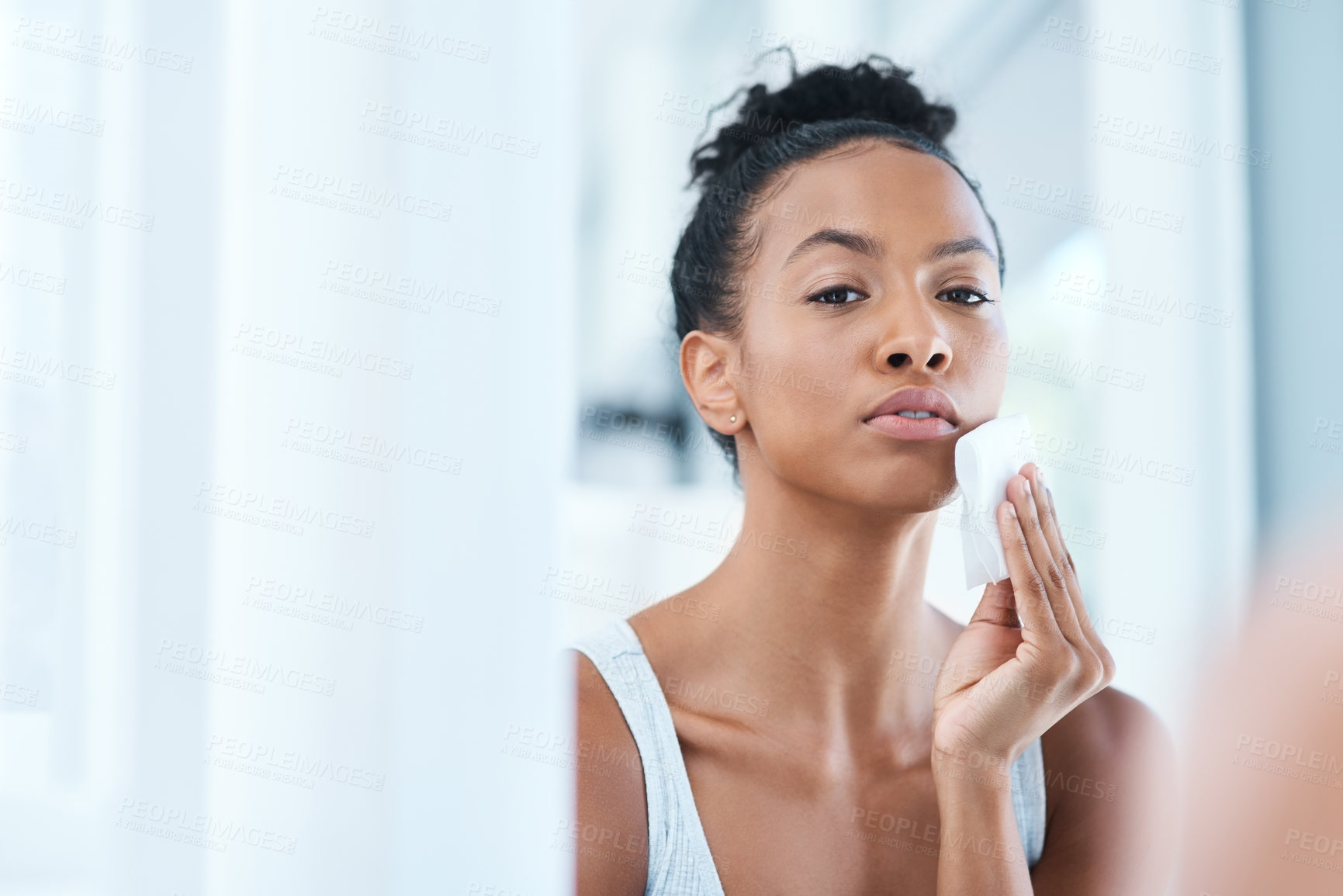 Buy stock photo Portrait of an attractive young woman cleaning her face with a cotton pad in the bathroom at home