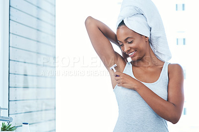 Buy stock photo Shot of an attractive young woman shaving her underarms with a razor in the bathroom