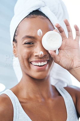 Buy stock photo Shot of a beautiful young woman applying moisturizer to her face