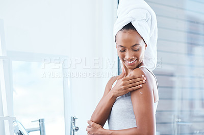 Buy stock photo Shot of a young woman applying moisturizer to her body
