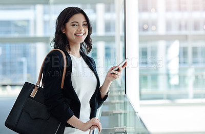 Buy stock photo Cropped portrait of an attractive young businesswoman smiling while using a smartphone in a modern office
