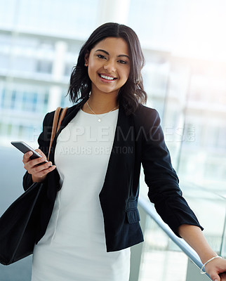 Buy stock photo Cropped portrait of an attractive young businesswoman smiling while holding a smartphone in a modern office