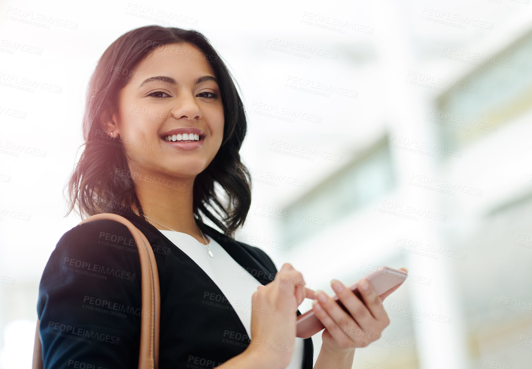 Buy stock photo Cropped portrait of an attractive young businesswoman smiling while using a smartphone in a modern office