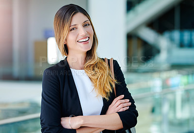 Buy stock photo Cropped portrait of an attractive young businesswoman smiling while standing with her arms crossed in a modern office