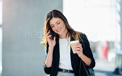Buy stock photo Cropped shot of an attractive young businesswoman taking a a phonecall while walking through a modern office
