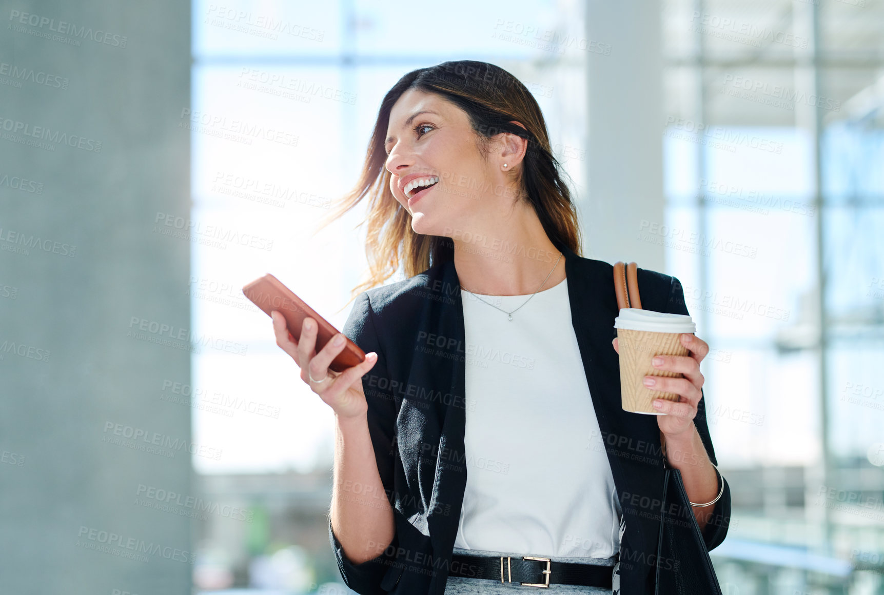 Buy stock photo Cropped shot of an attractive young businesswoman using a smartphone while walking through a modern office