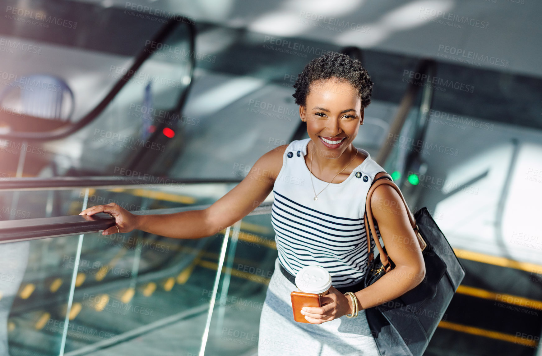 Buy stock photo Cropped portrait of an attractive young businesswoman smiling while taking an escalator in a modern workplace