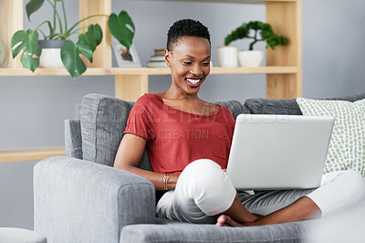 Buy stock photo Shot of a young woman relaxing on the sofa at home and using a laptop