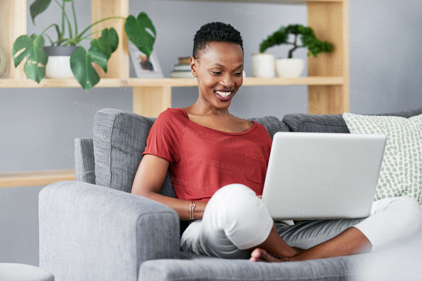 Buy stock photo Shot of a young woman relaxing on the sofa at home and using a laptop