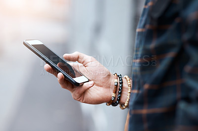 Buy stock photo Shot of an unrecognizable man using his cellphone in the city
