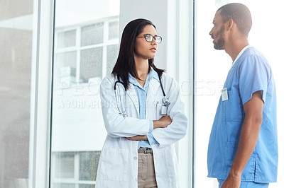 Buy stock photo Shot of two young doctors having a discussion in a modern hospital