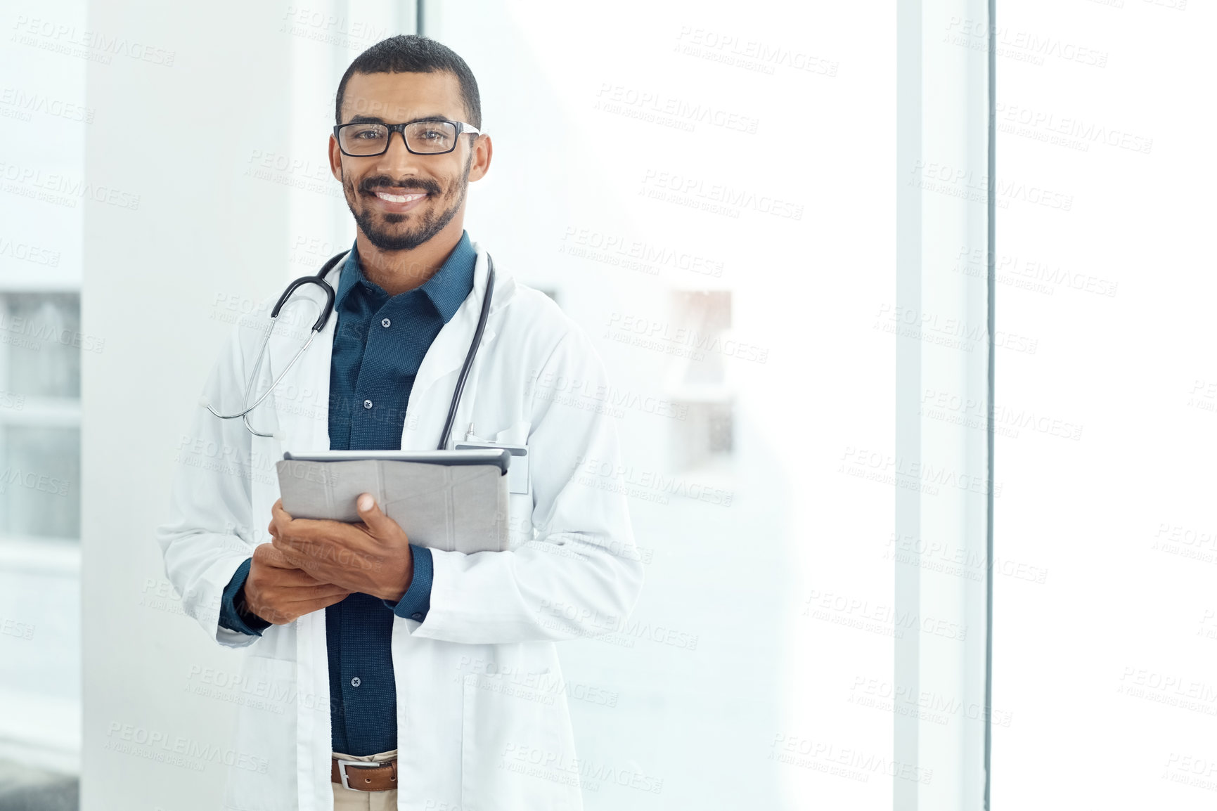 Buy stock photo Portrait of a young doctor holding a digital tablet in a modern hospital