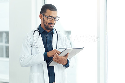 Buy stock photo Shot of a young doctor using a digital tablet in a modern hospital