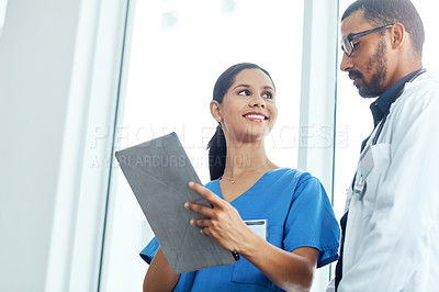 Buy stock photo Shot of two young doctors using a digital tablet in a modern hospital