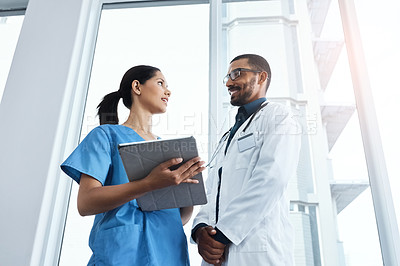 Buy stock photo Shot of two young doctors using a digital tablet in a modern hospital