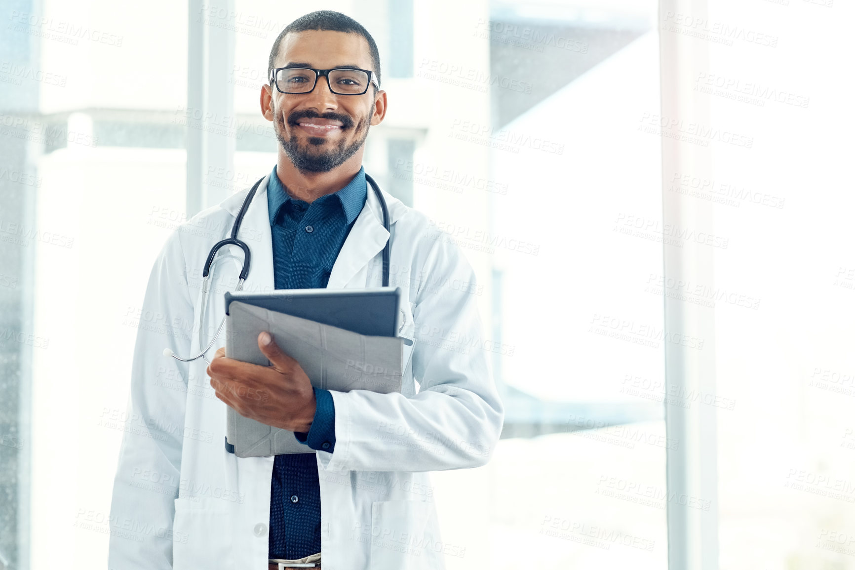 Buy stock photo Portrait of a young doctor holding a digital tablet in a modern hospital