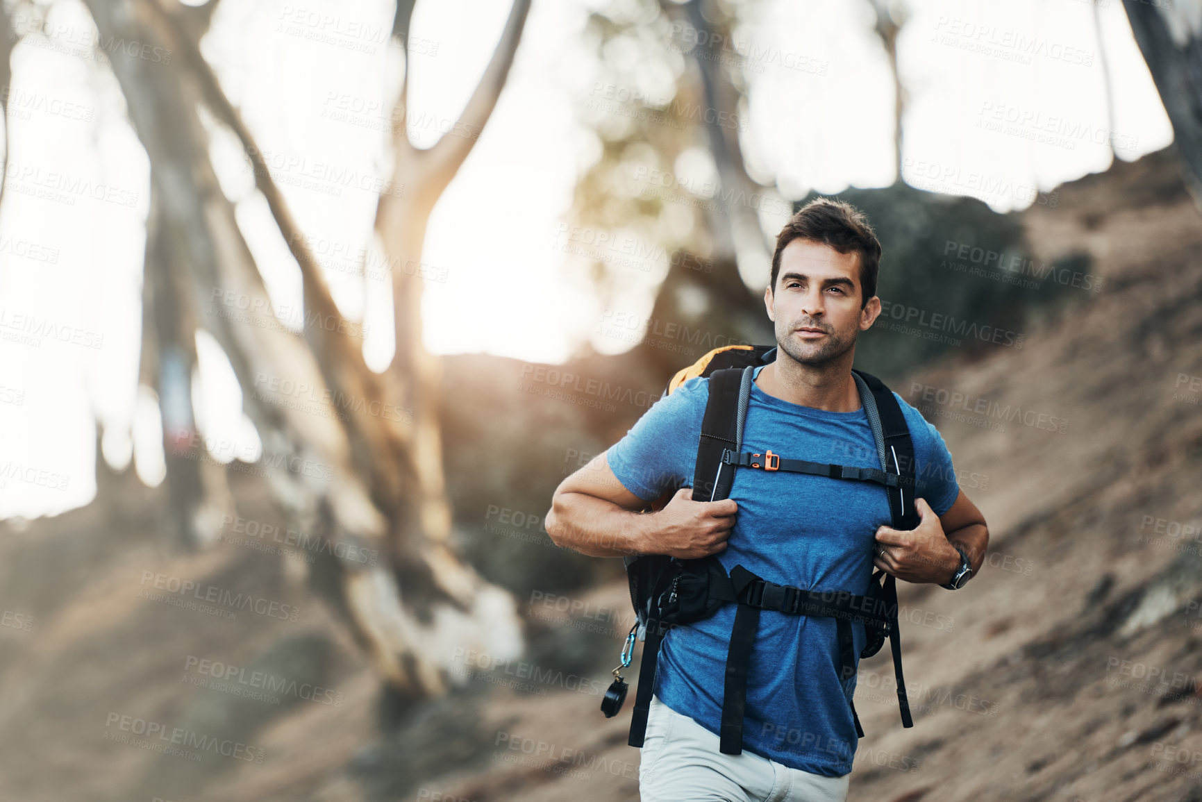 Buy stock photo Cropped shot of a cheerful young man wearing a backpack and ready to hike up a mountain