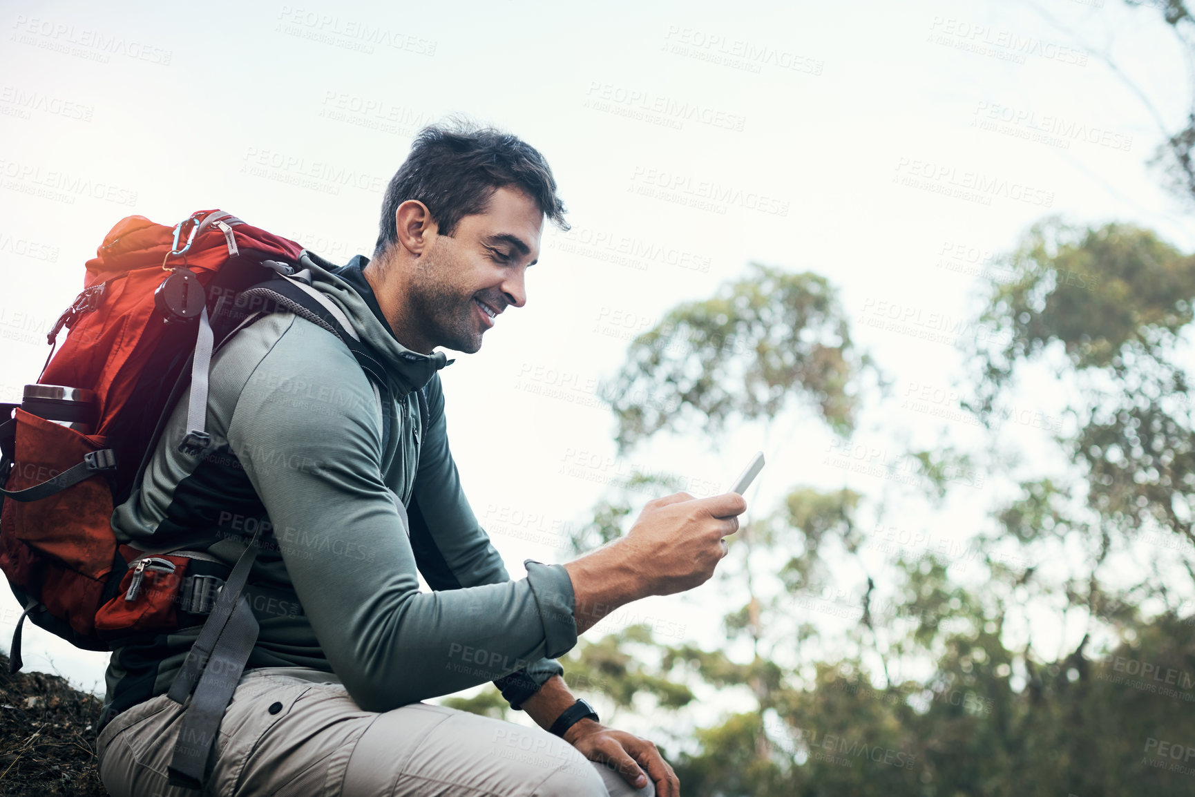 Buy stock photo Phone, chat and hiking man in forest with backpack for fitness, training and location, search or path planning. Smartphone, smile or athlete in park with map, direction or sport app for step tracking