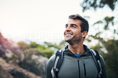 Buy stock photo Cropped shot of a cheerful young man looking into the distance while going for a hike up a mountain
