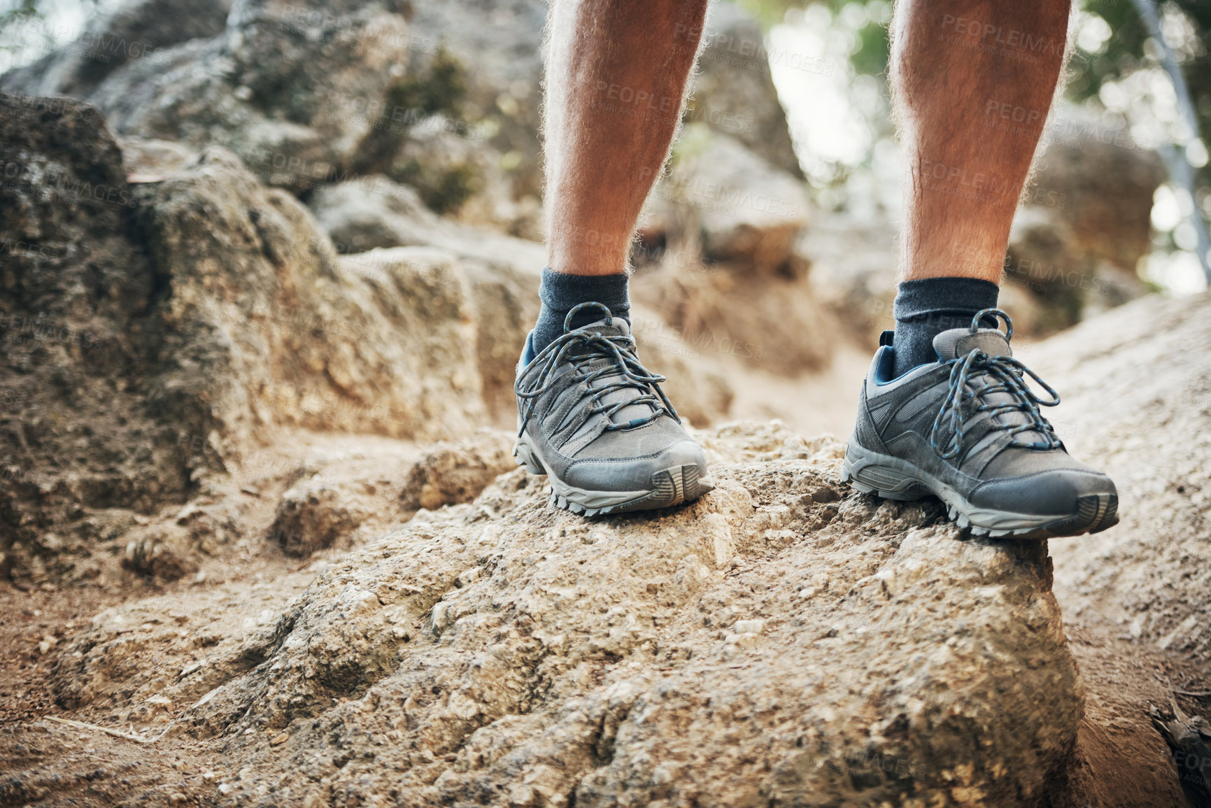 Buy stock photo Low angle shot of an unrecognizable man walking on rocks up a mountain outside during the day