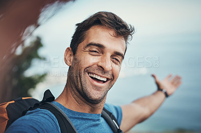 Buy stock photo Portrait of a cheerful young man taking a self portrait with his cellphone while going for a hike up a mountain