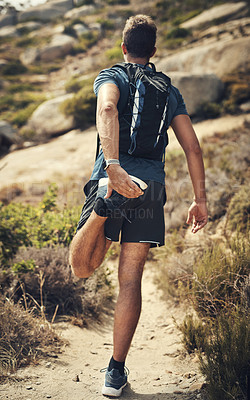 Buy stock photo Rearview shot of an unrecognizable young man stretching before heading off on his hike in the mountains